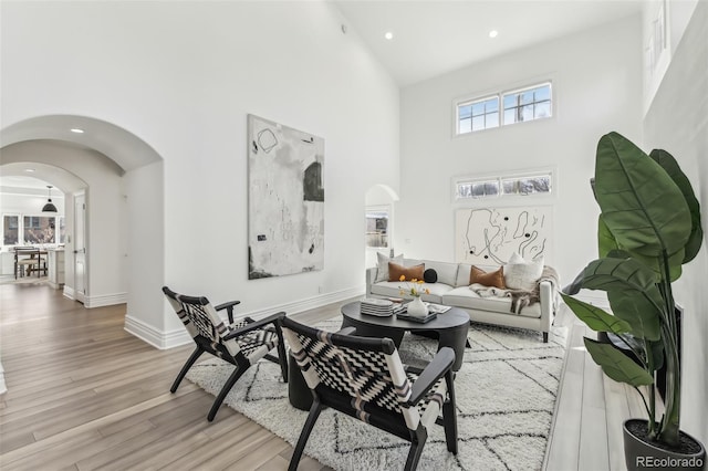 living area with wood finished floors, arched walkways, and high vaulted ceiling