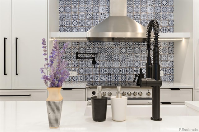 details with white cabinetry, light countertops, and wall chimney range hood