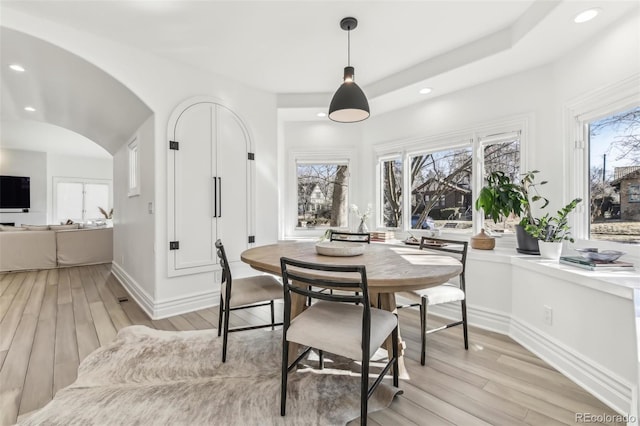 dining area featuring a wealth of natural light, arched walkways, recessed lighting, and light wood finished floors