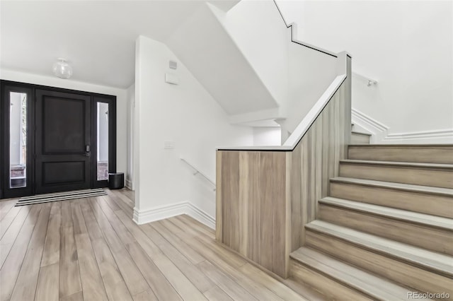 foyer featuring stairs, lofted ceiling, baseboards, and light wood finished floors