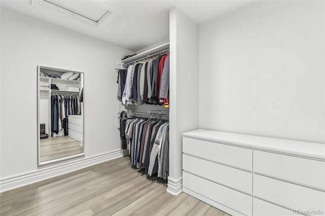 spacious closet with light wood-style flooring and attic access