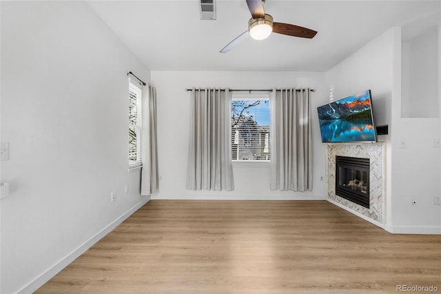 unfurnished living room featuring visible vents, ceiling fan, baseboards, a fireplace, and light wood-style floors