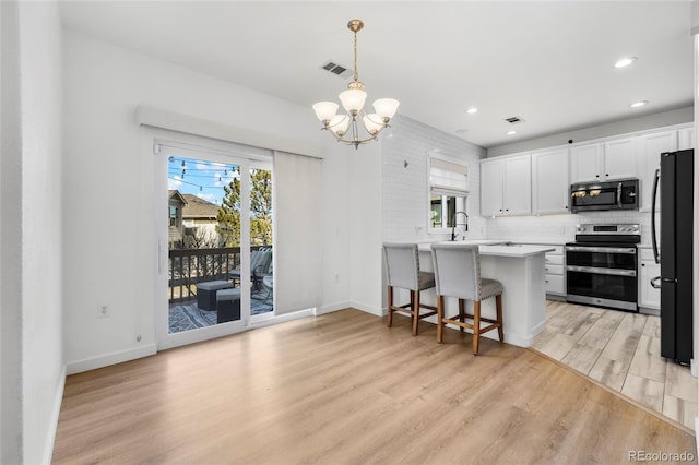 kitchen featuring a healthy amount of sunlight, visible vents, range with two ovens, freestanding refrigerator, and light wood-style floors