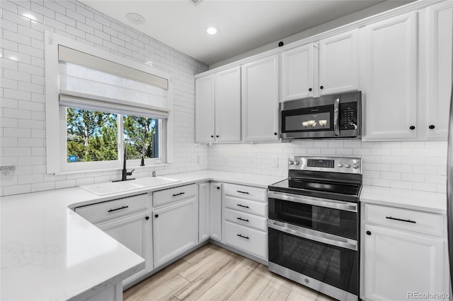 kitchen featuring a sink, backsplash, appliances with stainless steel finishes, and light countertops