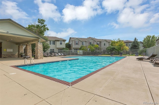 community pool featuring a patio area, fence, and a residential view