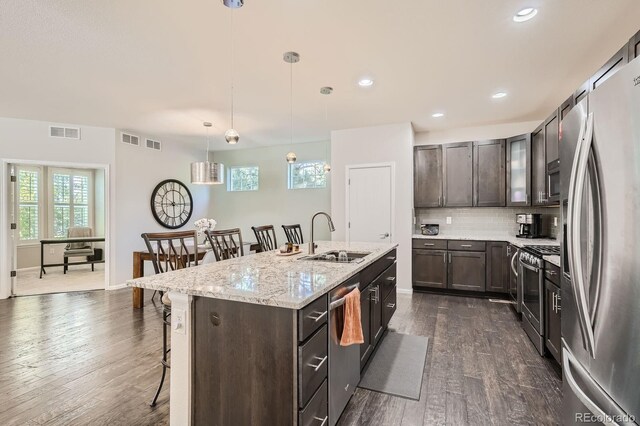 9523 Gray Ct, Westminster, CO 80031 - kitchen featuring stainless steel appliances, a kitchen bar, dark brown cabinets, decorative backsplash, and recessed lighting