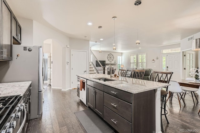9523 Gray Ct, Westminster, CO 80031 - kitchen with a kitchen bar, arched walkways, dark wood-type flooring, appliances with stainless steel finishes, and an island with sink