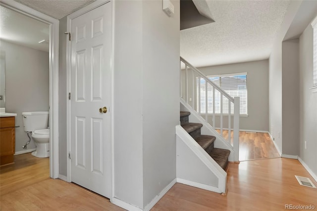 staircase with hardwood / wood-style flooring and a textured ceiling