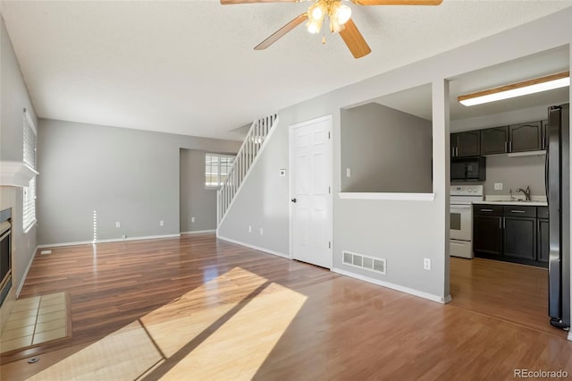 unfurnished living room featuring ceiling fan, dark hardwood / wood-style floors, sink, and a textured ceiling