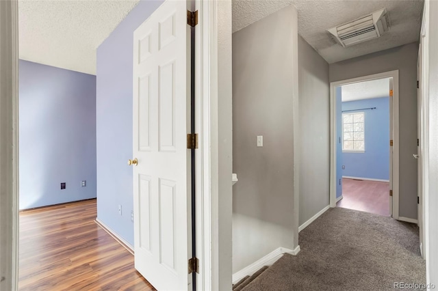 corridor featuring wood-type flooring and a textured ceiling