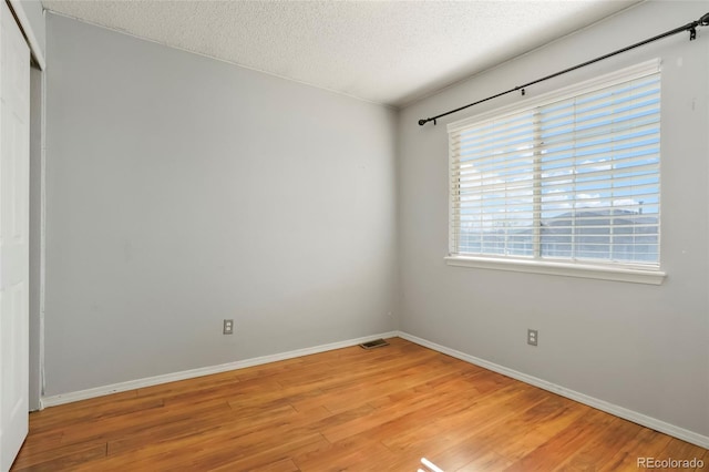 empty room featuring a textured ceiling and light wood-type flooring