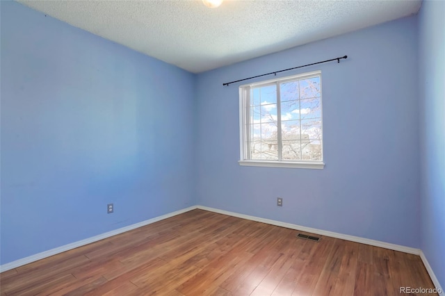 empty room featuring wood-type flooring and a textured ceiling