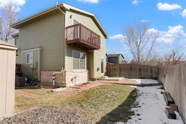 rear view of house featuring a balcony, a yard, and central AC unit