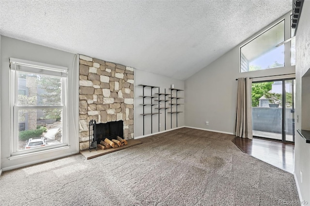 9797 E Peakview Ave Unit C10, Englewood, CO 80111 - unfurnished living room featuring carpet flooring, lofted ceiling, a textured ceiling, a stone fireplace, and baseboards