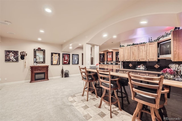 12693 W 82nd Ln, Arvada, CO 80005 - kitchen featuring a breakfast bar, recessed lighting, light brown cabinets, light colored carpet, and backsplash