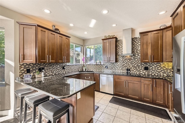 12693 W 82nd Ln, Arvada, CO 80005 - kitchen with appliances with stainless steel finishes, wall chimney exhaust hood, a peninsula, dark stone countertops, and backsplash