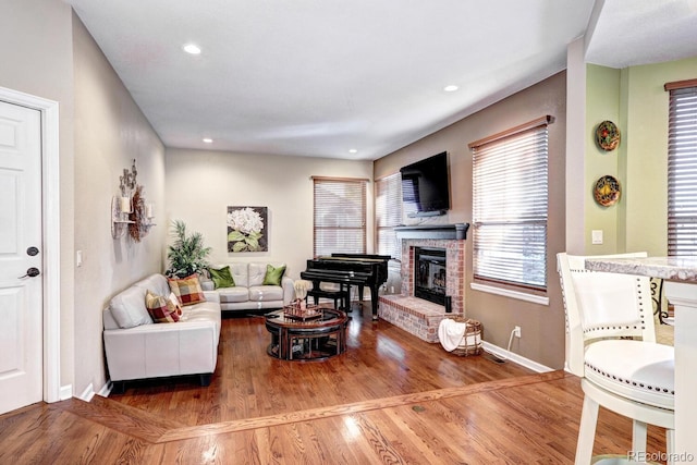 living room with a brick fireplace and wood-type flooring