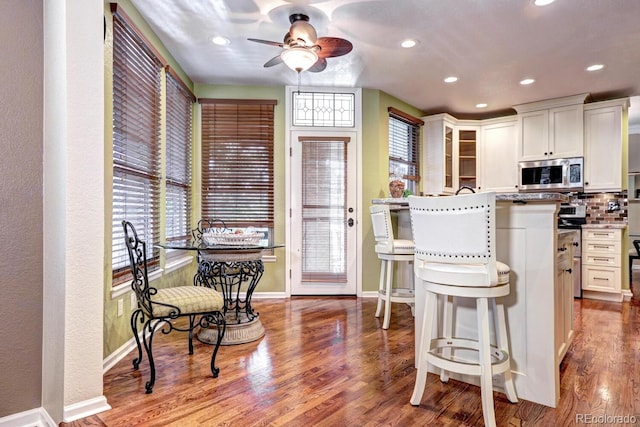 kitchen with white cabinetry, plenty of natural light, a kitchen breakfast bar, and light hardwood / wood-style flooring