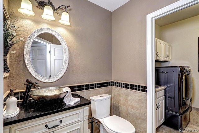 bathroom with vanity, separate washer and dryer, tile walls, and toilet