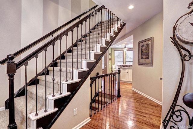 stairs featuring hardwood / wood-style floors and ceiling fan