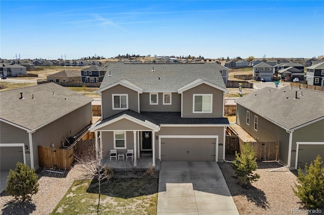 traditional home featuring driveway, roof with shingles, a residential view, fence, and an attached garage