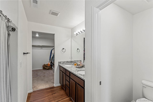full bath featuring toilet, visible vents, wood finished floors, and a spacious closet