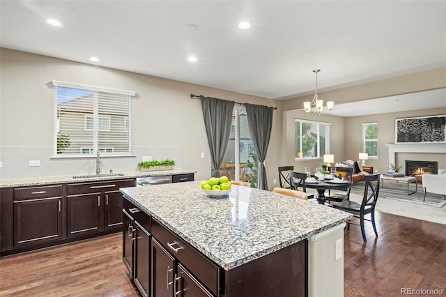 kitchen featuring pendant lighting, a chandelier, a center island, dark wood-type flooring, and sink