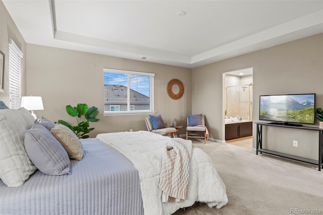 bedroom featuring a tray ceiling, ensuite bath, and light colored carpet