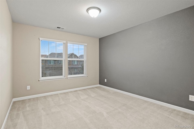 empty room featuring a textured ceiling and light carpet