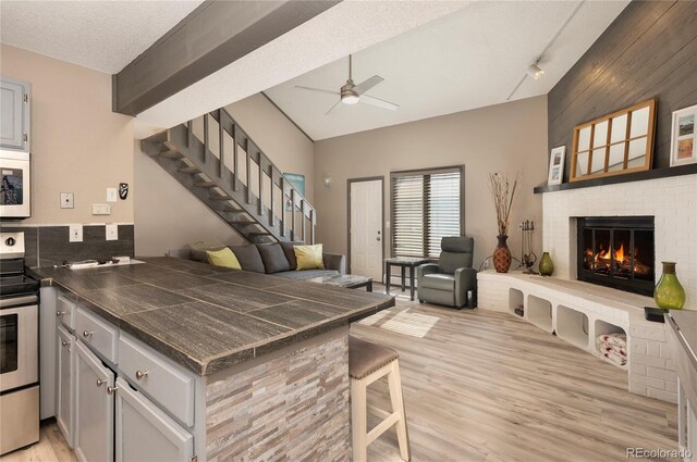 kitchen featuring a fireplace, light hardwood / wood-style floors, electric stove, kitchen peninsula, and a textured ceiling