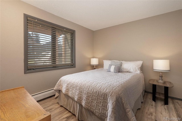 bedroom featuring a baseboard radiator and light hardwood / wood-style flooring