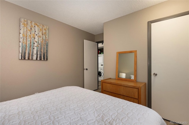 bedroom featuring a textured ceiling and stacked washer and dryer