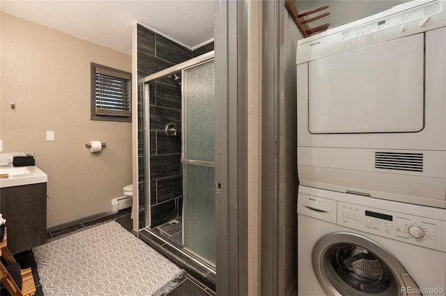 clothes washing area featuring tile patterned flooring, baseboard heating, and stacked washing maching and dryer