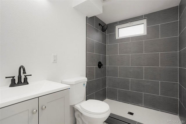 bathroom featuring tiled shower, vanity, and toilet