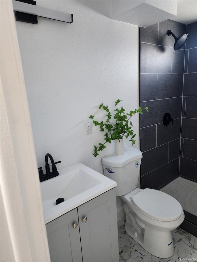 bathroom featuring tiled shower, vanity, and toilet