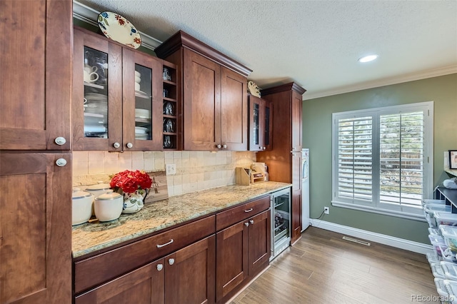 kitchen featuring light stone counters, wine cooler, dark wood-style flooring, tasteful backsplash, and glass insert cabinets