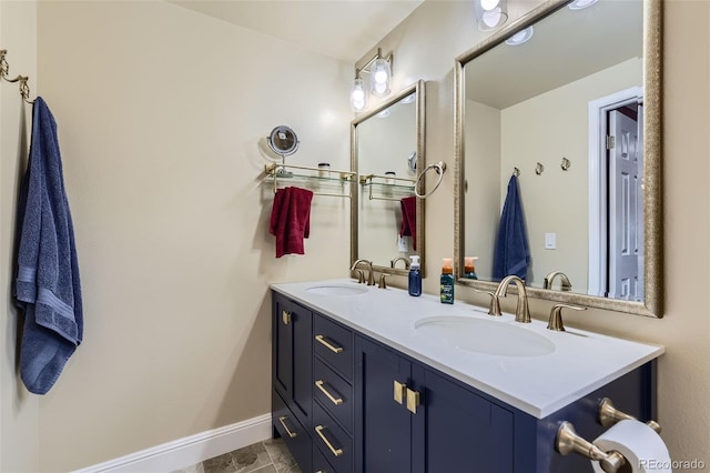 bathroom featuring double vanity, baseboards, and a sink