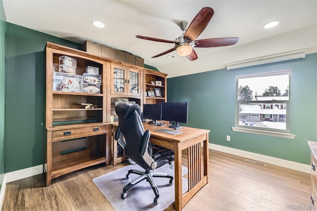 home office featuring visible vents, baseboards, ceiling fan, vaulted ceiling, and light wood-type flooring