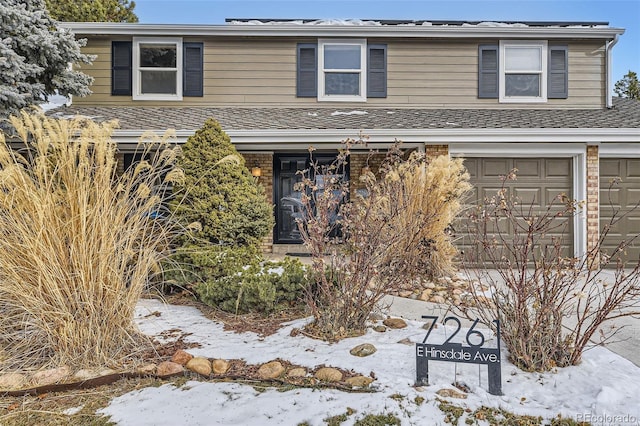 traditional-style home with an attached garage, brick siding, and a shingled roof