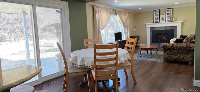 dining room with visible vents, dark wood finished floors, a tile fireplace, crown molding, and recessed lighting