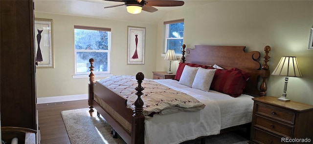 bedroom with dark wood-style floors, multiple windows, visible vents, and baseboards