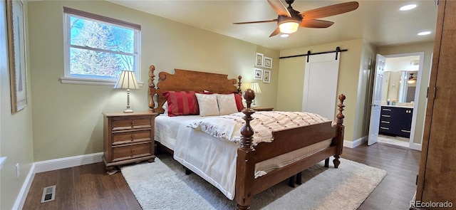 bedroom featuring dark wood-style floors, a barn door, visible vents, and baseboards