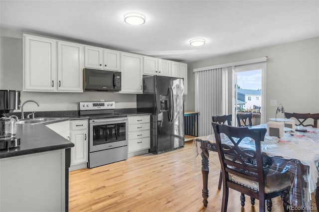5771 W 92nd Ave Unit 328, Westminster, CO 80031 - kitchen with black appliances, dark countertops, white cabinetry, and light wood-style flooring