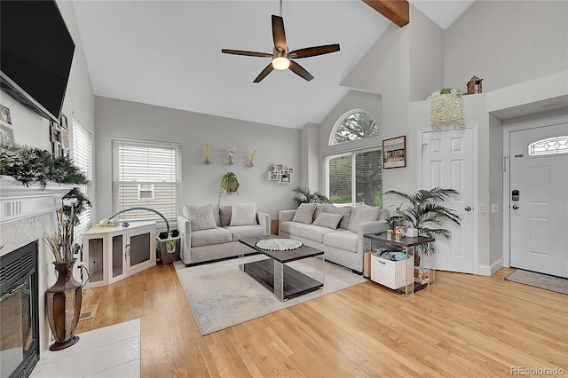 living room featuring plenty of natural light, a fireplace, high vaulted ceiling, and light hardwood / wood-style flooring