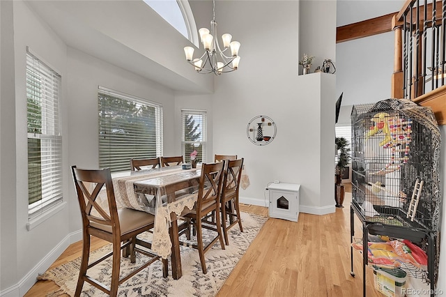 dining room featuring a high ceiling, an inviting chandelier, and light hardwood / wood-style flooring