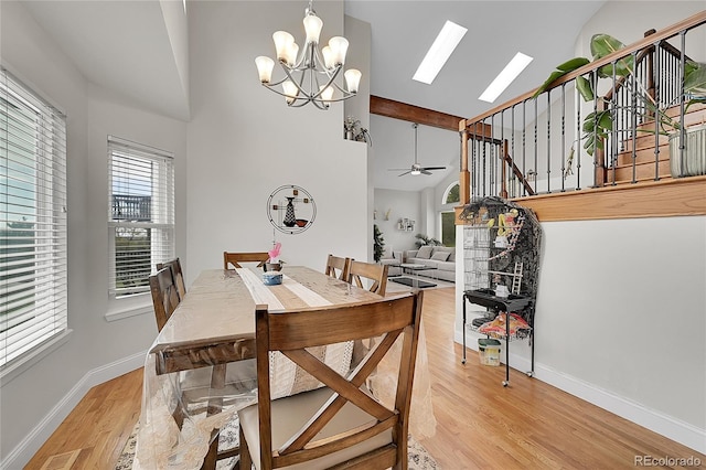 dining area featuring ceiling fan with notable chandelier, high vaulted ceiling, and light hardwood / wood-style flooring