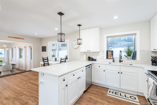 kitchen with sink, white cabinets, decorative light fixtures, kitchen peninsula, and stainless steel appliances