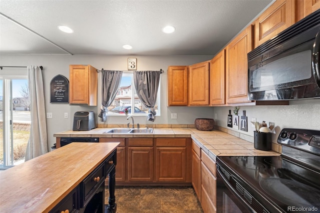 kitchen featuring sink, a textured ceiling, black appliances, and a healthy amount of sunlight