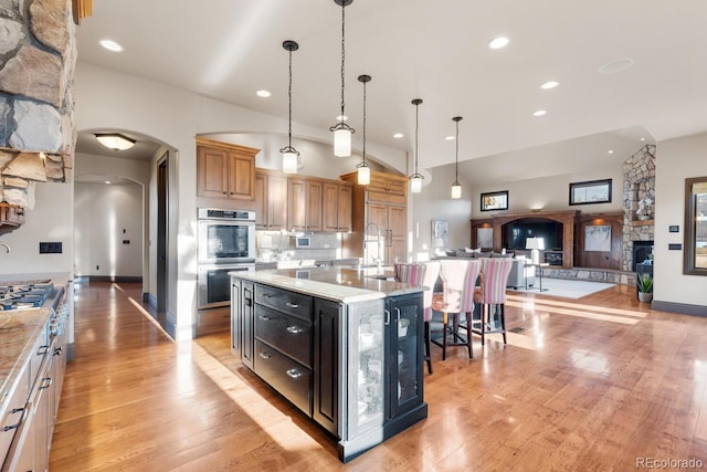 5810 Amber Ridge Dr, Castle Pines, CO 80108 - kitchen with arched walkways, stainless steel appliances, open floor plan, light wood-style flooring, and recessed lighting