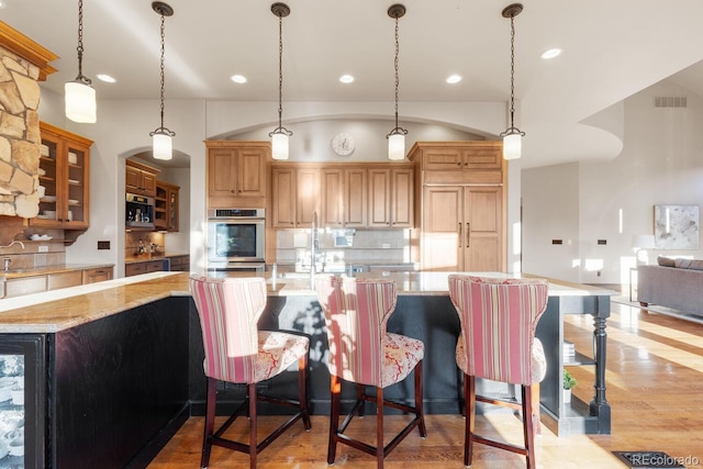 5810 Amber Ridge Dr, Castle Pines, CO 80108 - kitchen featuring stainless steel double oven, decorative backsplash, light wood-style floors, recessed lighting, and glass insert cabinets